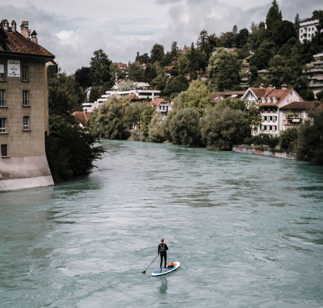 Man paddleboarding down river