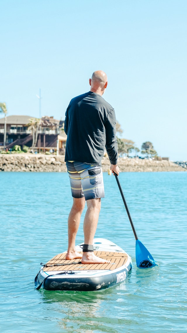 Close up of man paddleboarding on coast